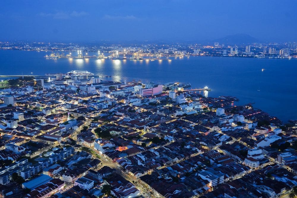 Aerial night view of George Town, Penang, with city lights and the mainland across the sea